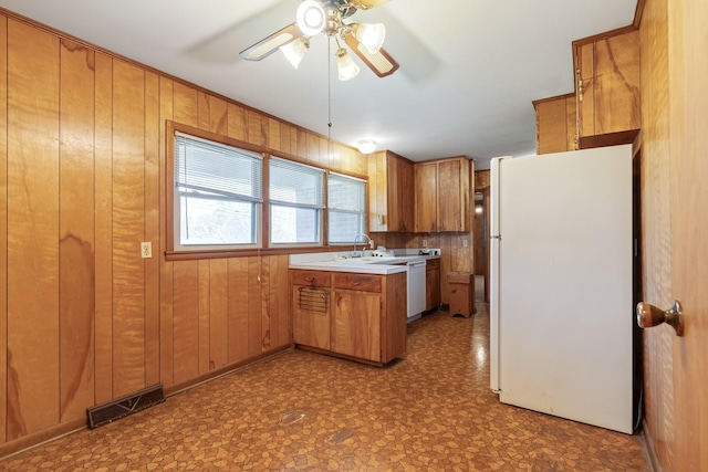 kitchen featuring white appliances, wooden walls, brown cabinetry, visible vents, and tile patterned floors