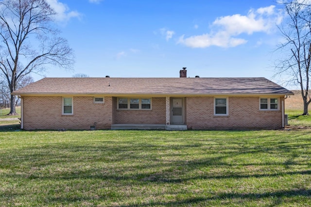 back of house with a yard, brick siding, and a chimney