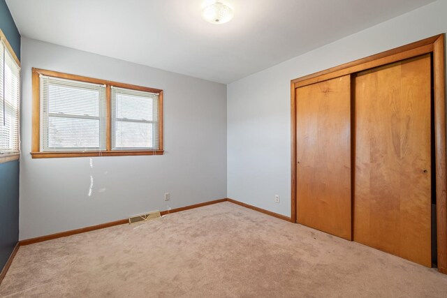 unfurnished bedroom featuring carpet, visible vents, a closet, and baseboards