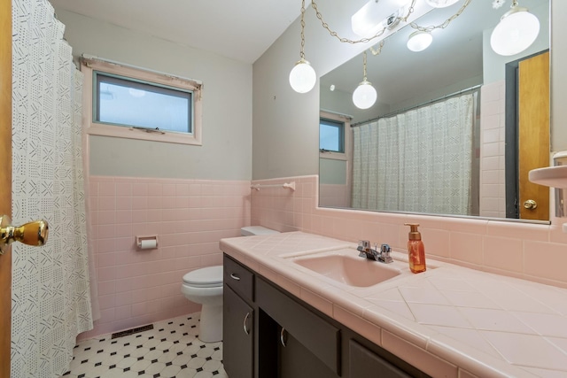 full bathroom featuring tile walls, toilet, a healthy amount of sunlight, and wainscoting