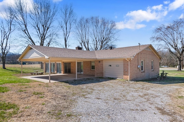 rear view of property with a patio, a shingled roof, a chimney, a lawn, and brick siding