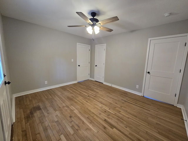 unfurnished bedroom featuring baseboards, wood finished floors, and a ceiling fan