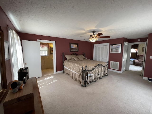 bedroom with visible vents, a ceiling fan, a textured ceiling, baseboards, and light colored carpet