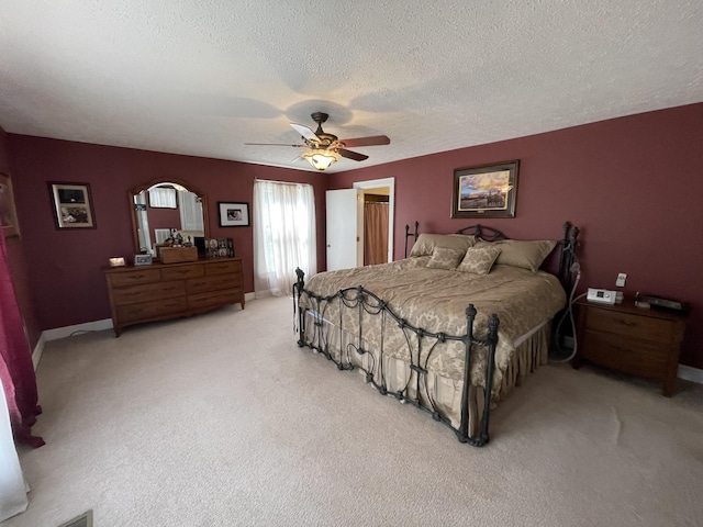 bedroom featuring light carpet, a ceiling fan, baseboards, and a textured ceiling