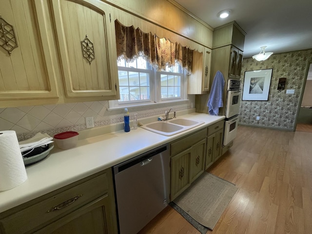 kitchen featuring wallpapered walls, light wood-style flooring, a sink, light countertops, and dishwasher