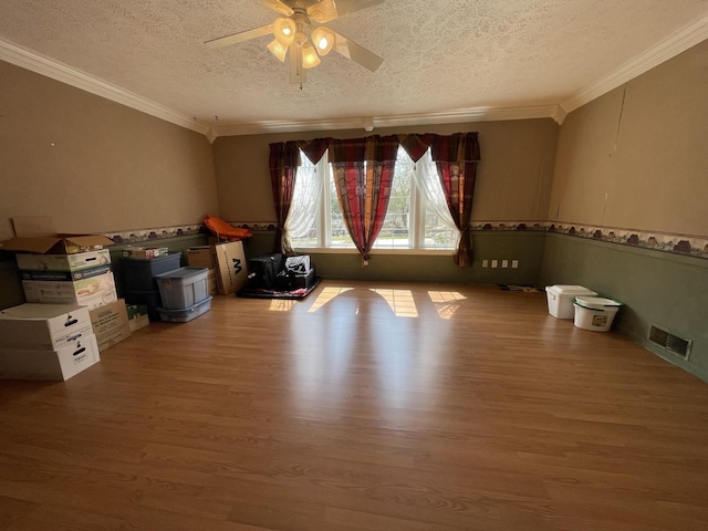 spare room featuring ceiling fan, visible vents, wood finished floors, and ornamental molding