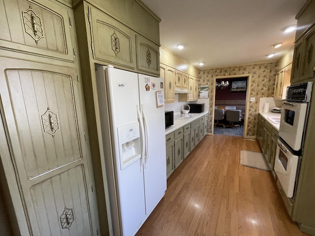 kitchen with wallpapered walls, white appliances, light wood-style flooring, and light countertops