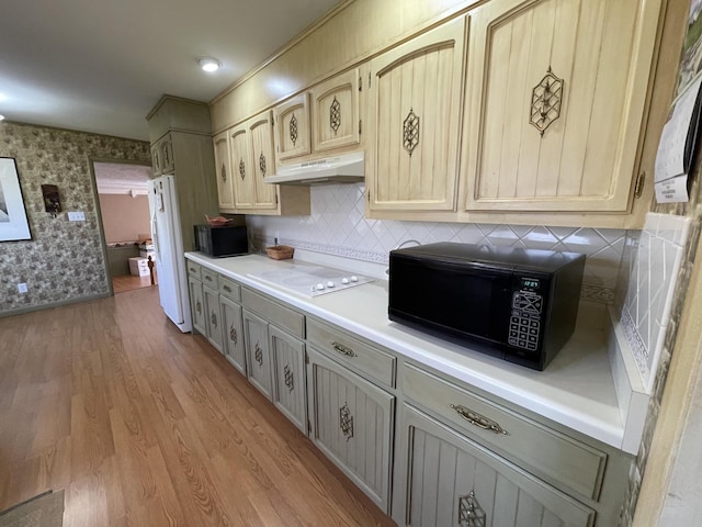 kitchen with wallpapered walls, under cabinet range hood, light countertops, light wood-style floors, and white appliances