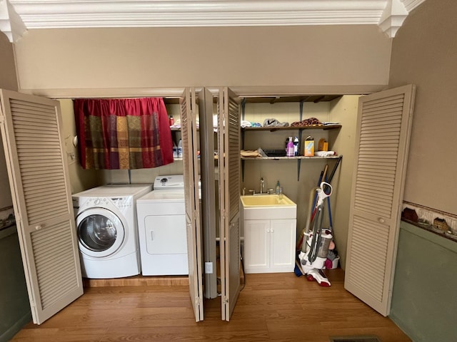 clothes washing area with laundry area, crown molding, wood finished floors, and independent washer and dryer