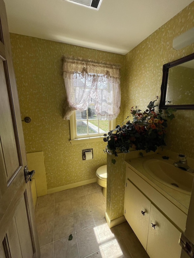 bathroom featuring tile patterned floors, toilet, wallpapered walls, baseboards, and vanity