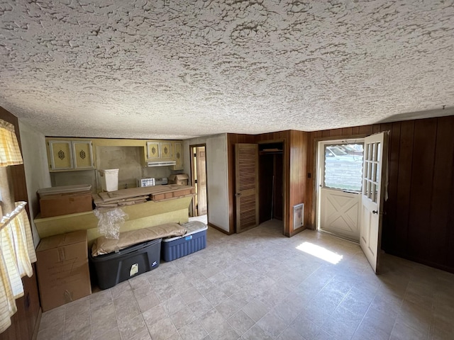 unfurnished bedroom featuring access to exterior, a closet, and wood walls