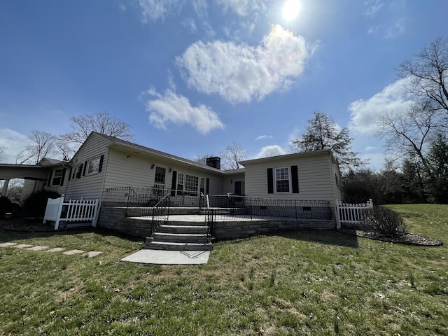 back of house with a lawn, a deck, fence, crawl space, and a chimney