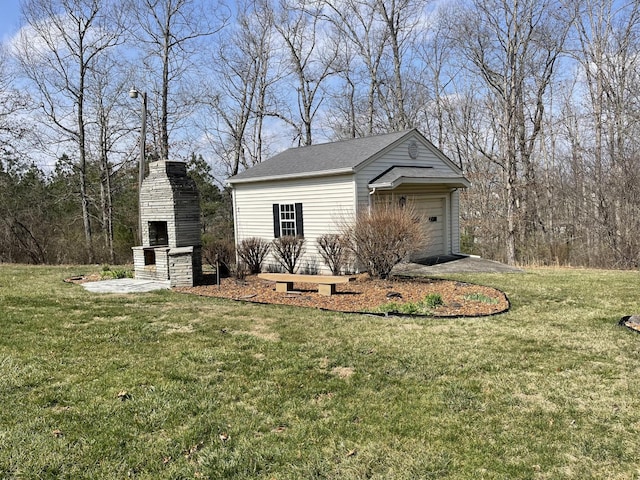 exterior space featuring aphalt driveway, an outbuilding, and an outdoor stone fireplace