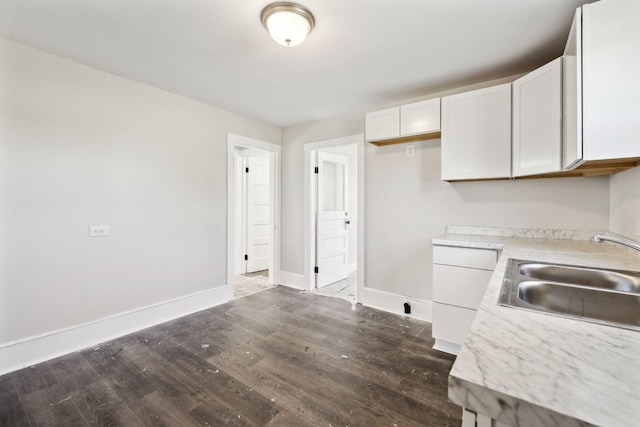 kitchen featuring a sink, white cabinets, light countertops, baseboards, and dark wood-style flooring