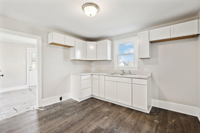 kitchen featuring dark wood-style floors, white cabinetry, baseboards, and a sink