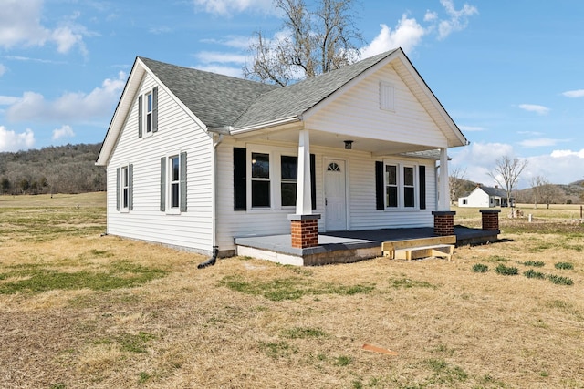 bungalow with a porch, a front lawn, and roof with shingles