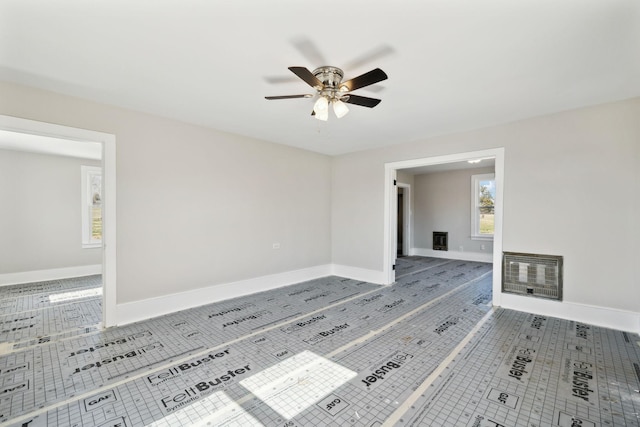 unfurnished room featuring tile patterned flooring, heating unit, a ceiling fan, and baseboards