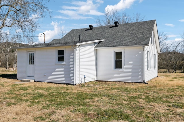 back of house with a lawn and roof with shingles