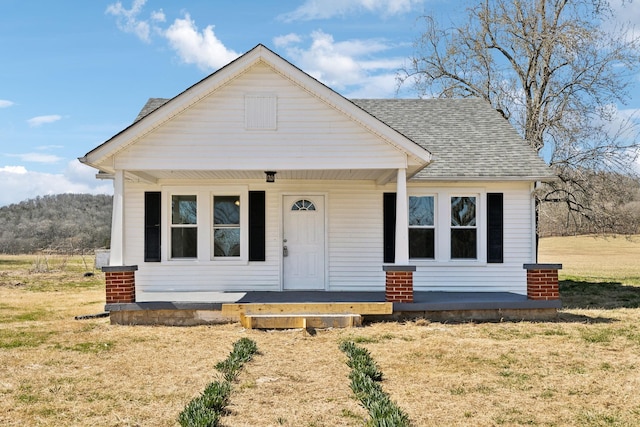 bungalow with covered porch, a front lawn, and a shingled roof