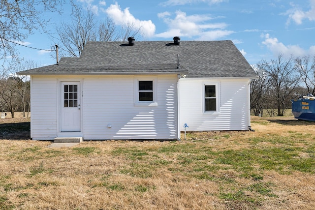 rear view of property featuring a yard and a shingled roof