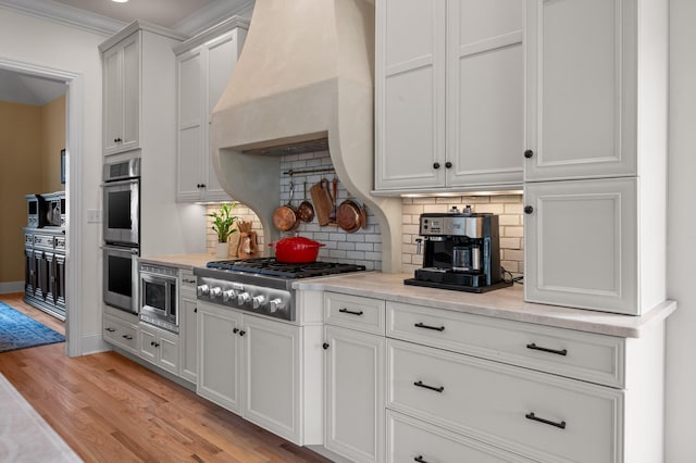 kitchen with premium range hood, light wood-style floors, appliances with stainless steel finishes, and light countertops