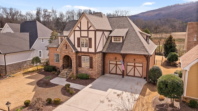 view of front of home with stucco siding, stone siding, roof with shingles, and concrete driveway