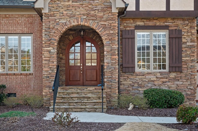 property entrance with stucco siding, french doors, stone siding, and crawl space