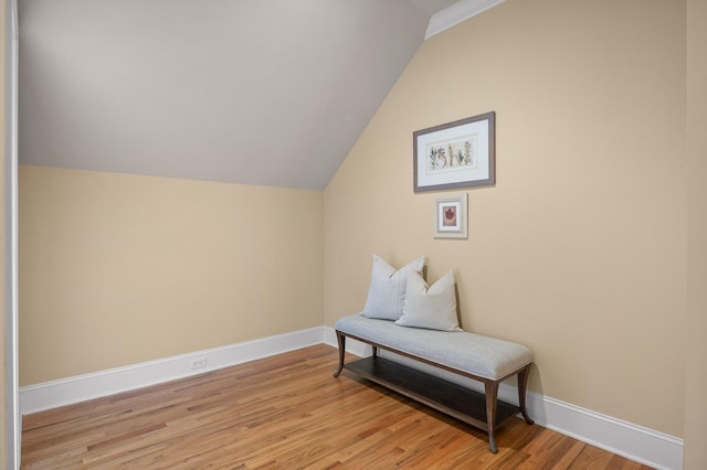 living area with baseboards, vaulted ceiling, and light wood finished floors