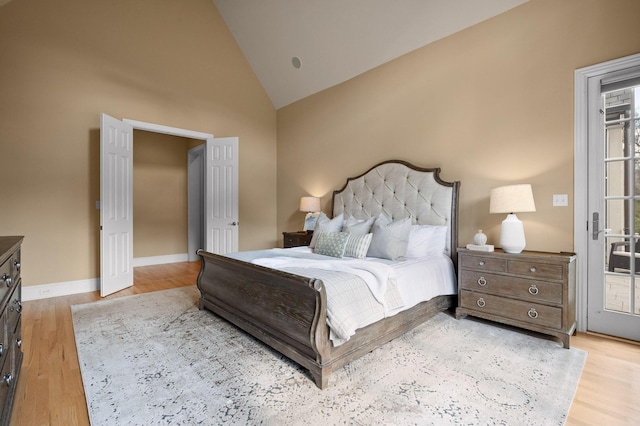 bedroom featuring access to exterior, wood finished floors, baseboards, and vaulted ceiling