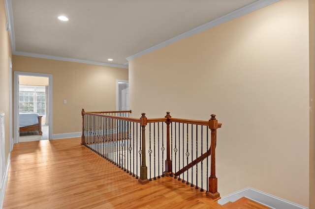 corridor featuring an upstairs landing, baseboards, light wood finished floors, and ornamental molding
