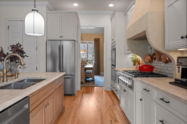 kitchen featuring a sink, appliances with stainless steel finishes, ornamental molding, and light countertops
