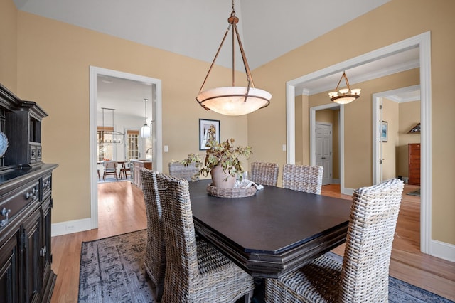 dining space featuring a chandelier, crown molding, light wood-type flooring, and baseboards