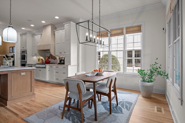 dining area with a notable chandelier, visible vents, light wood finished floors, and ornamental molding