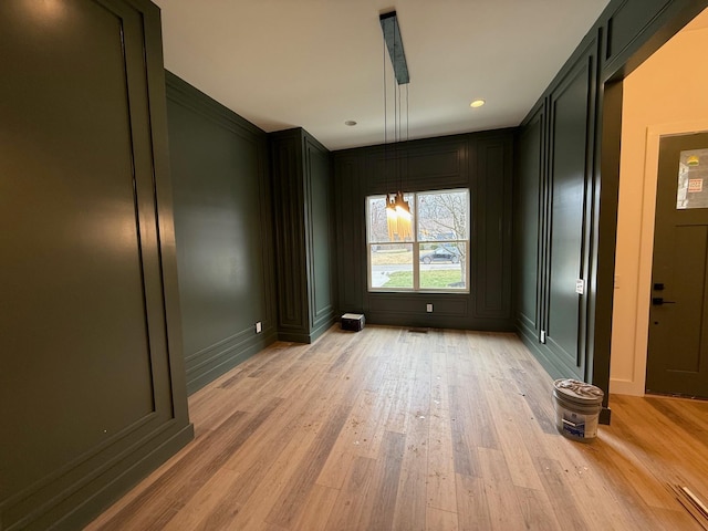 empty room featuring light wood finished floors and a decorative wall