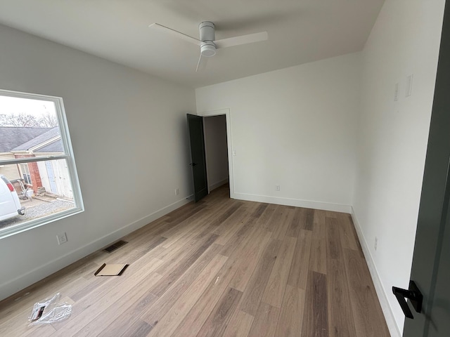 empty room featuring light wood-style flooring, baseboards, visible vents, and ceiling fan