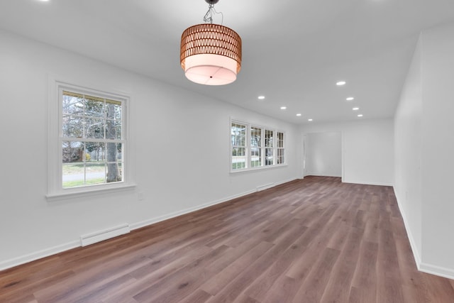 spare room featuring recessed lighting, wood finished floors, baseboards, and a wealth of natural light