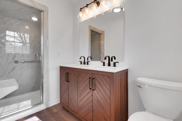 full bath with a marble finish shower, wood finished floors, toilet, and a sink