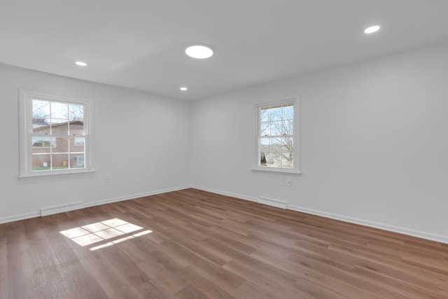 unfurnished room with recessed lighting, wood finished floors, visible vents, and a wealth of natural light