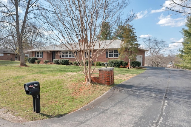 ranch-style home featuring a front yard, brick siding, a garage, and driveway