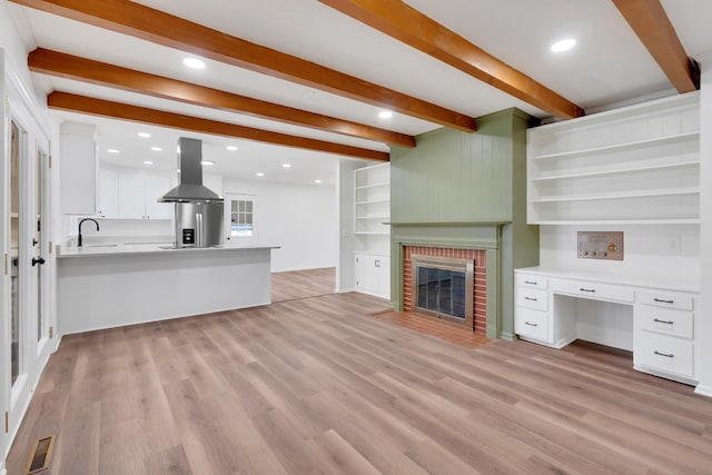 unfurnished living room with beamed ceiling, visible vents, recessed lighting, light wood finished floors, and a brick fireplace