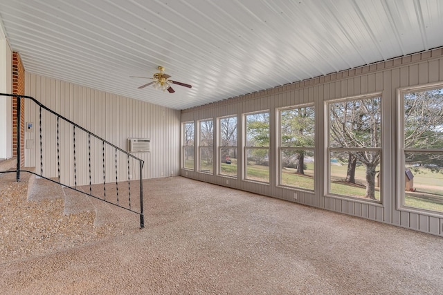 unfurnished sunroom featuring a ceiling fan and a wall mounted AC