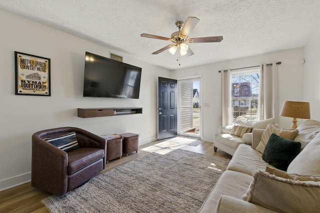 living area with ceiling fan, baseboards, a textured ceiling, and wood finished floors