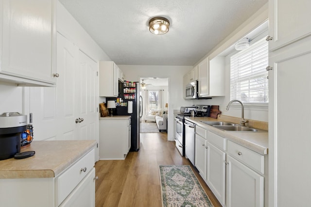 kitchen featuring plenty of natural light, stainless steel appliances, light wood-type flooring, and a sink