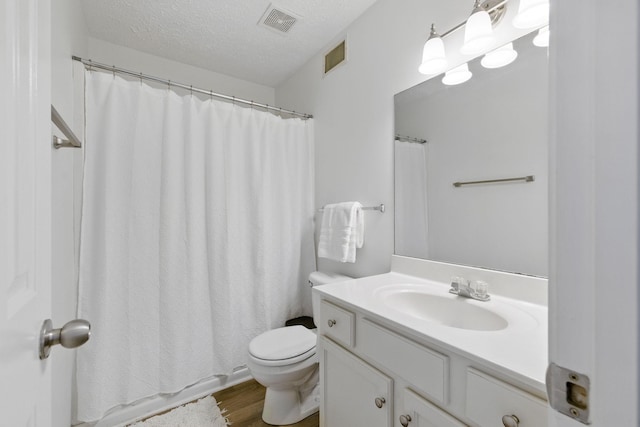 full bathroom featuring vanity, toilet, visible vents, and a textured ceiling