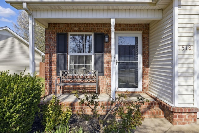 doorway to property with brick siding and covered porch