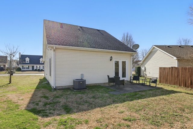 rear view of house featuring central air condition unit, a lawn, fence, a shingled roof, and a patio area