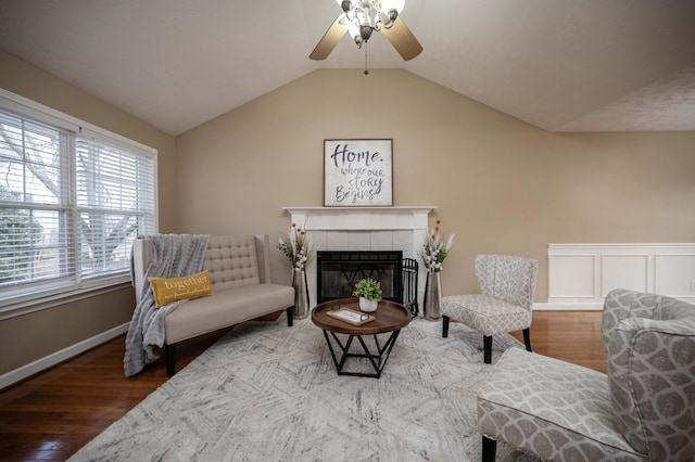 living room featuring a tiled fireplace, vaulted ceiling, wood finished floors, and ceiling fan