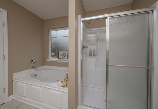 bathroom featuring a textured ceiling, a jetted tub, a stall shower, and tile patterned flooring