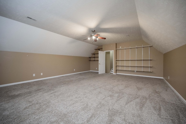 additional living space featuring baseboards, visible vents, a textured ceiling, and ceiling fan