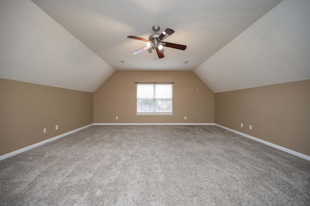 additional living space featuring a ceiling fan, baseboards, carpet floors, vaulted ceiling, and a textured ceiling